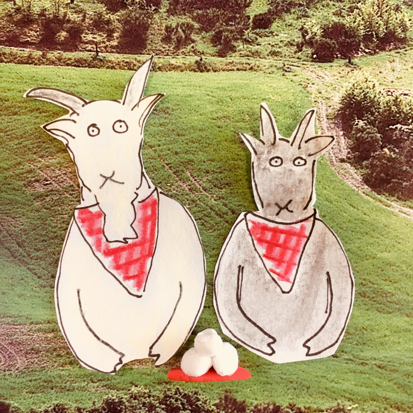 Image of two hand drawn goats wearing red bibs placed over a hill landscape with cheese in from of them
