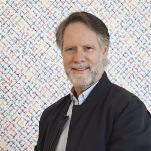 Author Michael Levitt stands in front of an abstract, patterned background